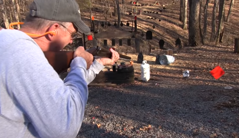 men with an Ithaca Classic Double Barrel 12 Gauge Coach Gun pointing at a target 
