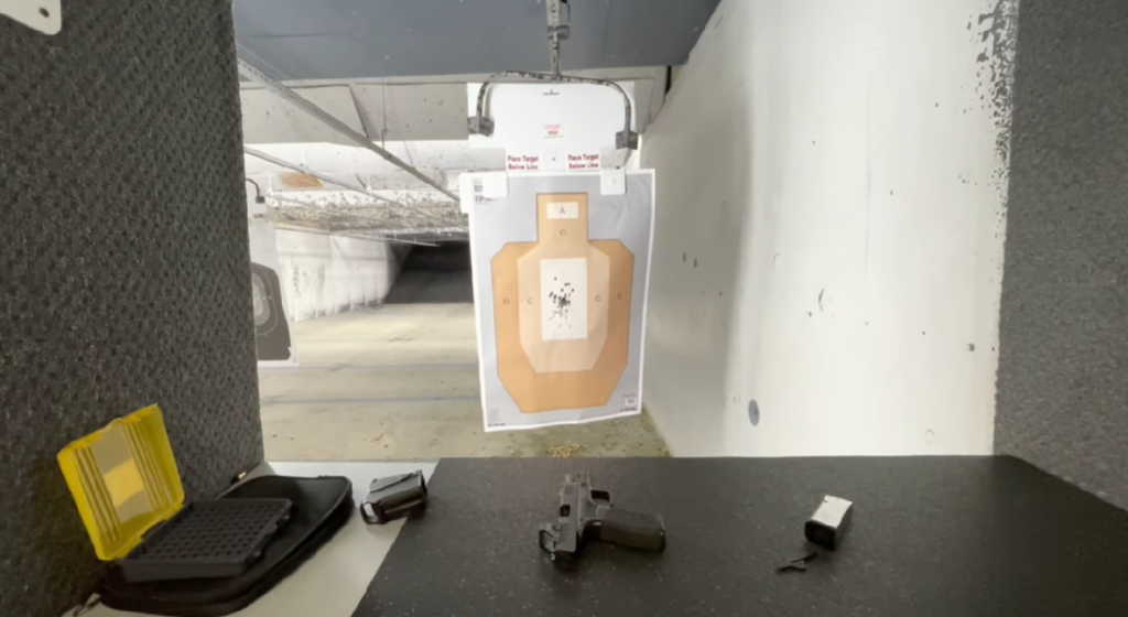 shooting stall with a handgun, case and accessories on the table an a shooting target paper in front